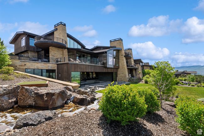 Back of house with a chimney, a balcony, and stone siding | Image 73