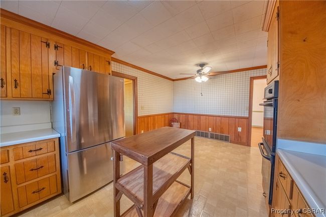 Kitchen featuring ornamental molding, multiple ovens, ceiling fan, and stainless steel refrigerator | Image 15