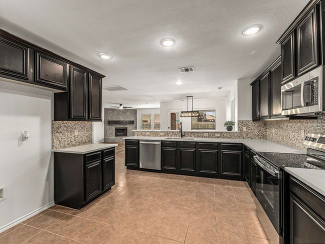 Kitchen featuring stainless steel appliances, tasteful backsplash, open floor plan, a ceiling fan, and a textured ceiling | Image 16