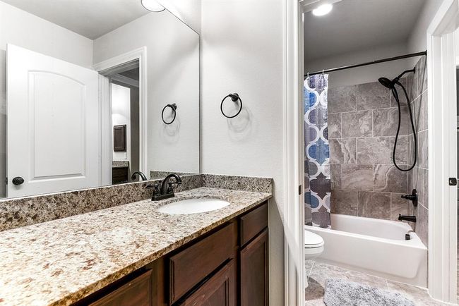 This generously sized guest bathroom features spacious countertops with plenty of cabinet storage for all your essentials and a shower-tub combo. | Image 37
