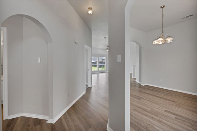 Corridor with wood finished floors, arched walkways, baseboards, and a chandelier | Image 7