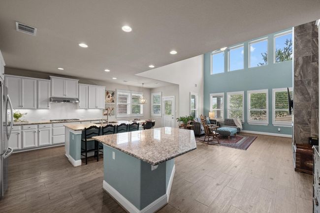 Kitchen with a center island with sink, under cabinet range hood, appliances with stainless steel finishes, a breakfast bar, and open floor plan | Image 14