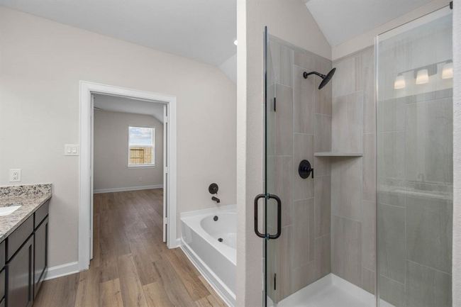 This en-suite bathroom is the epitome of modern luxury. It features a separate tub and shower combination for the ultimate in comfort and convenience. The sleek vanity and mirror provide a stylish focal point, and the thoughtfully designed layout adds to the luxurious feel of this private retreat. | Image 5