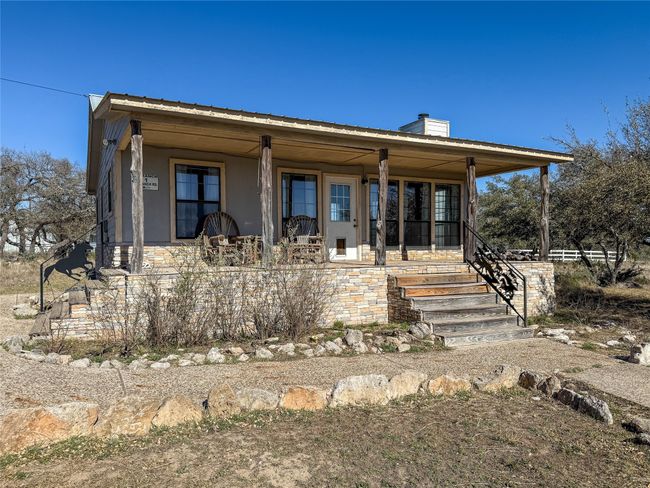 Rear view of house with covered porch, stone siding, stucco siding, and a chimney | Image 6