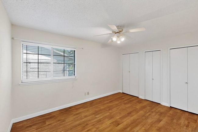 Unfurnished bedroom with wood finished floors, two closets, ceiling fan, and a textured ceiling | Image 18
