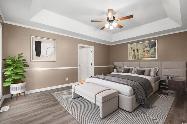 Bedroom with a tray ceiling, wood finished floors, and crown molding | Image 23