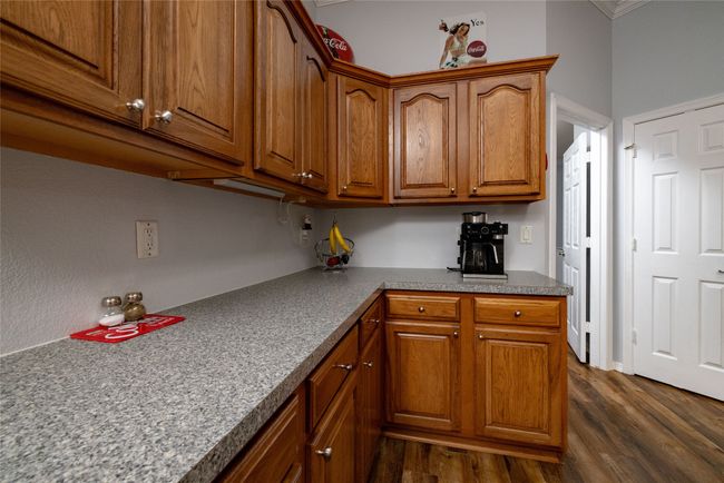 Kitchen with dark wood-style floors, brown cabinets, and crown molding | Image 20