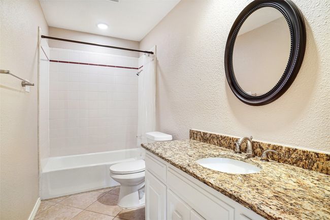 Full bathroom with toilet, shower / bath combo with shower curtain, vanity, tile patterned flooring, and a textured wall | Image 10