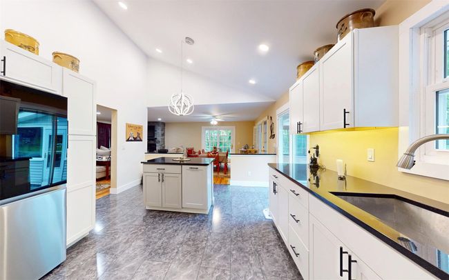 Kitchen with a sink, dark countertops, lofted ceiling, smart refrigerator, and hanging light fixtures | Image 21