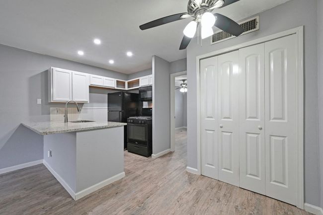 Kitchen featuring white cabinets, black appliances, recessed lighting, light wood-type flooring, and a peninsula | Image 12
