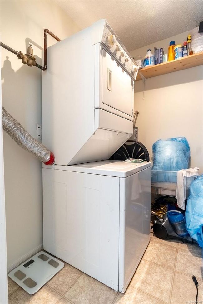 Clothes washing area with a textured ceiling and stacked washer / drying machine | Image 14