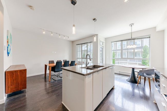 Kitchen featuring dark wood-style flooring, white cabinets, track lighting, decorative light fixtures, and a chandelier | Image 10