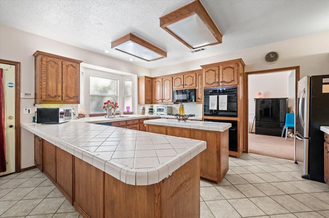 Island kitchen offers tons of counterspace for easy meal preparations and entertaining. Bay window over the sink offers a gorgeous view of the sparkling pool. | Image 25