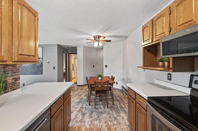 In this view from the kitchen looking down the hall you will see the second bedroom and full bathroom. There is a ceiling fan with a light in the dining room which provides a gentle breeze and air circulation throughout the home. | Image 8