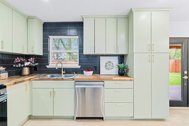 Kitchen featuring stainless steel dishwasher, butcher block countertops, and backsplash | Image 14