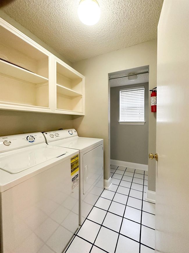 Clothes washing area featuring washing machine and clothes dryer, a textured ceiling, light tile patterned floors, and baseboards | Image 6