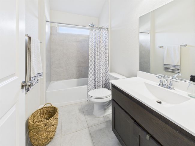 Full bath with shower / tub combo with curtain, toilet, tile patterned floors, and vanity | Image 9