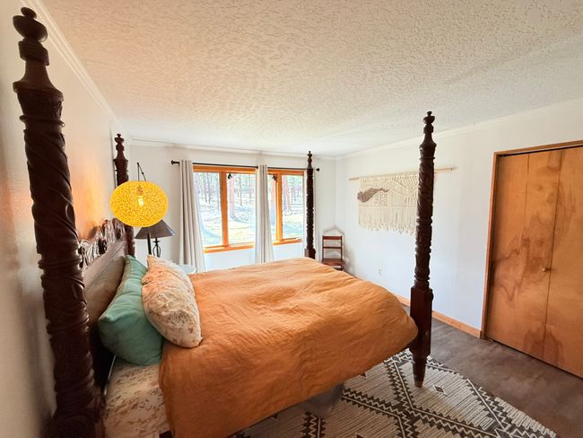 Bedroom with crown molding, wood finished floors, and a textured ceiling | Image 43