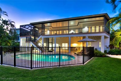 Back of house at dusk featuring fenced in pool, yard, patio, balcony | Image 2