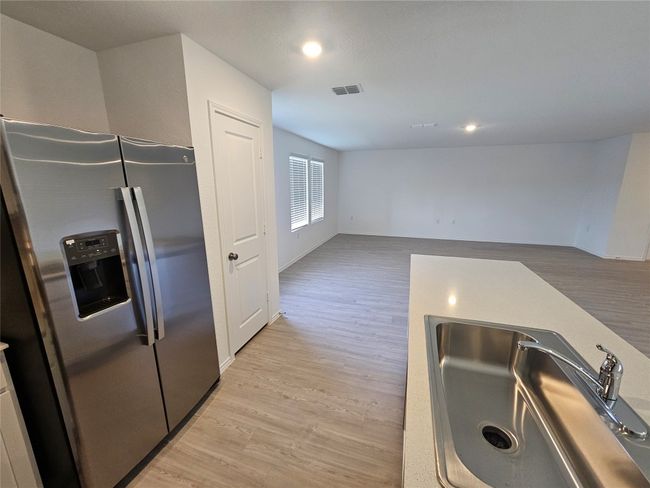 Kitchen featuring a sink, stainless steel fridge, visible vents, light wood-style flooring, and baseboards | Image 9