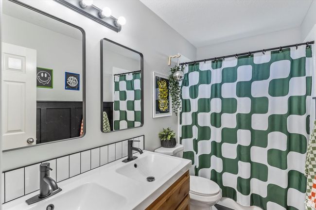 Full bath with toilet, double vanity, and a shower with curtain | Image 17