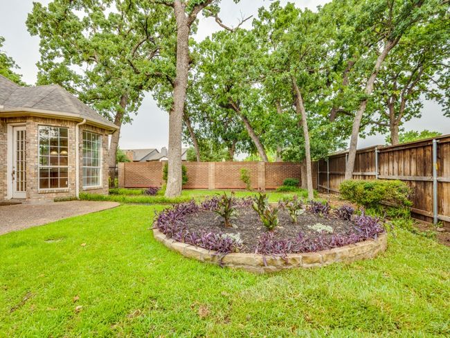 Fenced backyard with a patio. rock planter and mature trees. | Image 25
