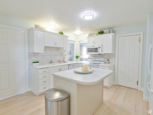 Kitchen featuring white appliances, a sink, light countertops, decorative backsplash, and a textured ceiling | Image 30