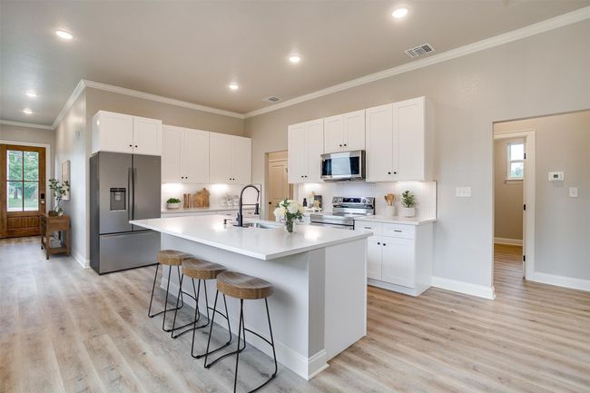Kitchen featuring a sink, appliances with stainless steel finishes, a kitchen breakfast bar, and light wood-style floors | Image 11