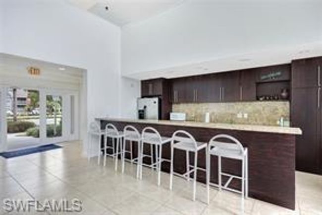 Kitchen with tasteful backsplash, freestanding refrigerator, dark brown cabinetry, light countertops, and a breakfast bar area | Image 27
