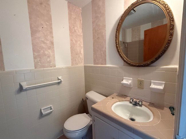 Half bathroom with tile walls, toilet, vanity, and wainscoting | Image 9