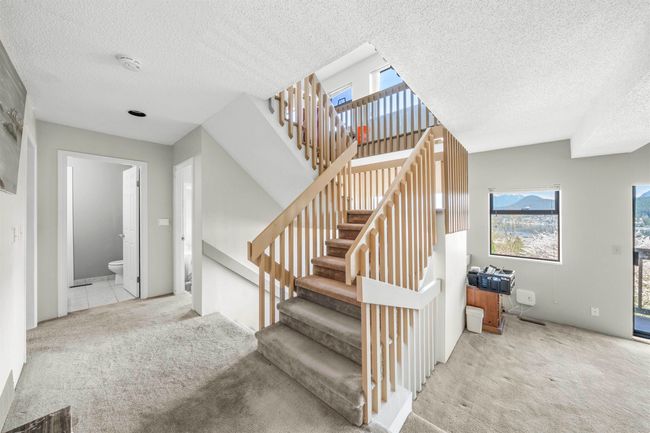 Stairway featuring a textured ceiling and carpet floors | Image 28