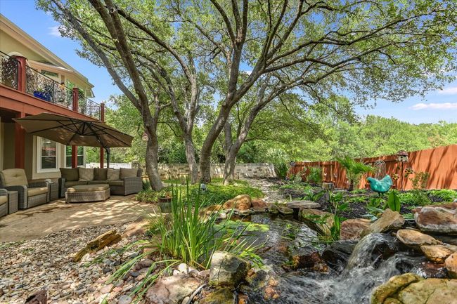 Fenced backyard featuring an outdoor hangout area, a balcony, a patio area, and a small pond | Image 25
