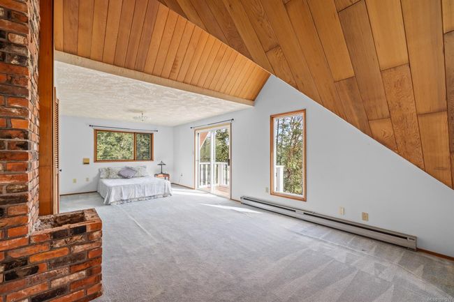 Unfurnished bedroom with a baseboard radiator, access to outside, carpet flooring, and wood ceiling | Image 23