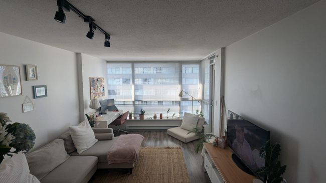 Living room with a textured ceiling, a baseboard radiator, floor to ceiling windows, track lighting, and wood finished floors | Image 4