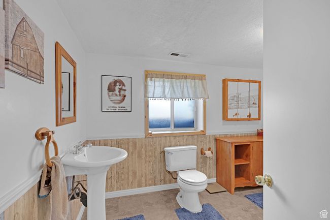 Bathroom with toilet, wainscoting, wooden walls, and a textured ceiling | Image 26