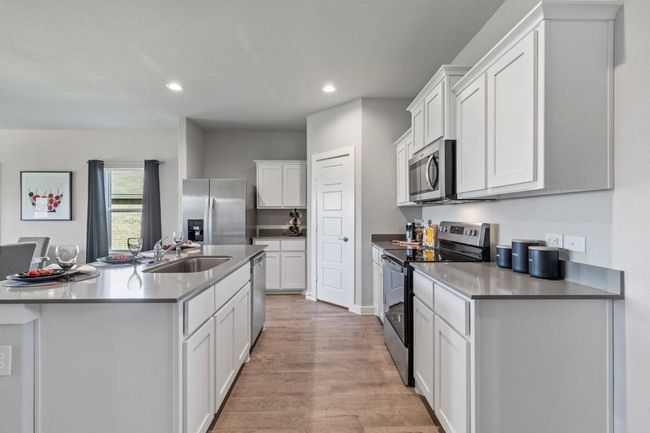 Kitchen with tile flooring, stainless steel appliances, an island with sink, white cabinetry, and sink. Virtually staged | Image 9
