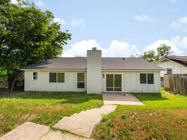 Back of property with board and batten siding, a chimney, a patio area, and roof with shingles | Image 25