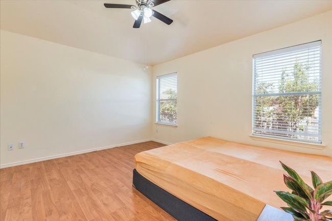 Bedroom with light wood-style floors, baseboards, and ceiling fan | Image 10