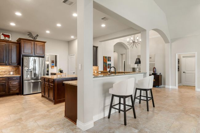 This beautiful kitchen equipped with a breakfast bar, recessed lighting, dark cabinetry, granite countertops and perfect for still hanging with all your guests with great access to your living room. | Image 12
