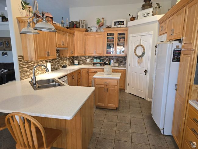 Kitchen featuring a sink, decorative backsplash, freestanding refrigerator, and a peninsula | Image 25