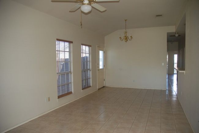 Unfurnished room featuring lofted ceiling, a ceiling fan, plenty of natural light, a chandelier, and light tile patterned floors | Image 4