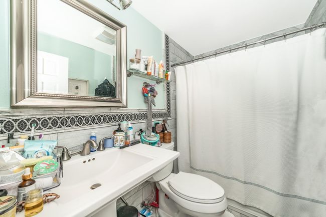 Bathroom with toilet, a shower with curtain, and decorative backsplash | Image 18