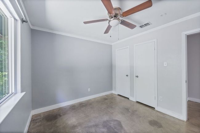Unfurnished bedroom featuring finished concrete floors, crown molding, and ceiling fan | Image 17