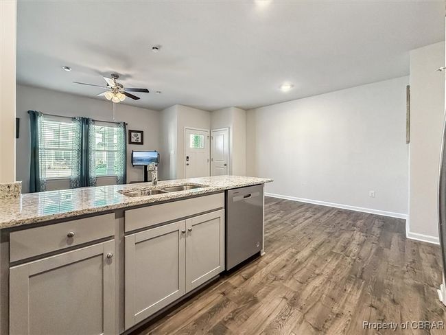 Kitchen with stainless steel dishwasher, dark wood-style floors, a ceiling fan, and a healthy amount of sunlight | Image 7