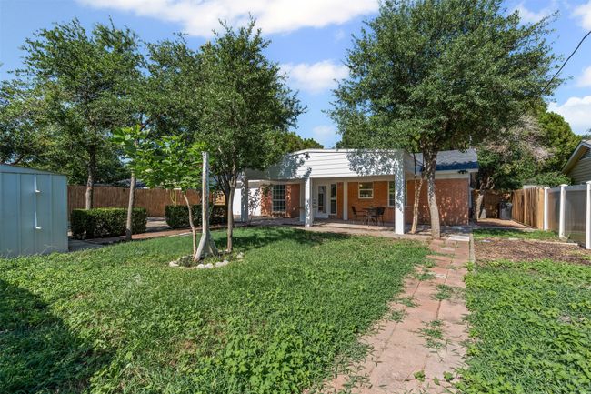 Rear view of house with a fenced backyard, a shed, brick siding, and a patio area | Image 28