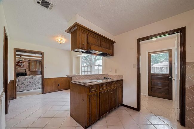 Experience culinary delight in this kitchen with a sleek new electric cooktop, inviting counter seating, and seamless access to the cozy breakfast nook. | Image 7