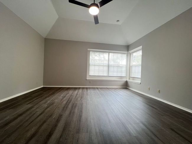 Empty room with dark wood-type flooring, a ceiling fan, and vaulted ceiling | Image 18