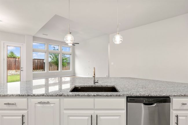 Kitchen with dishwasher, a sink, a ceiling fan, and white cabinetry | Image 10