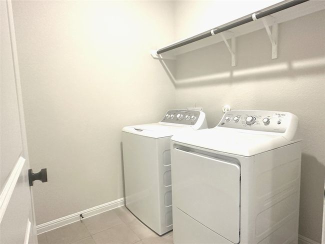 Washroom featuring washing machine and clothes dryer, light tile floors, and baseboards | Image 13