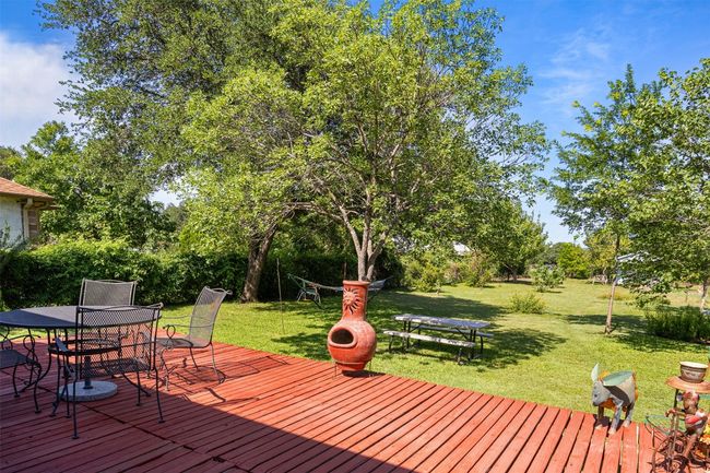 Deck with outdoor dining space, a lawn, and view of scattered trees | Image 32